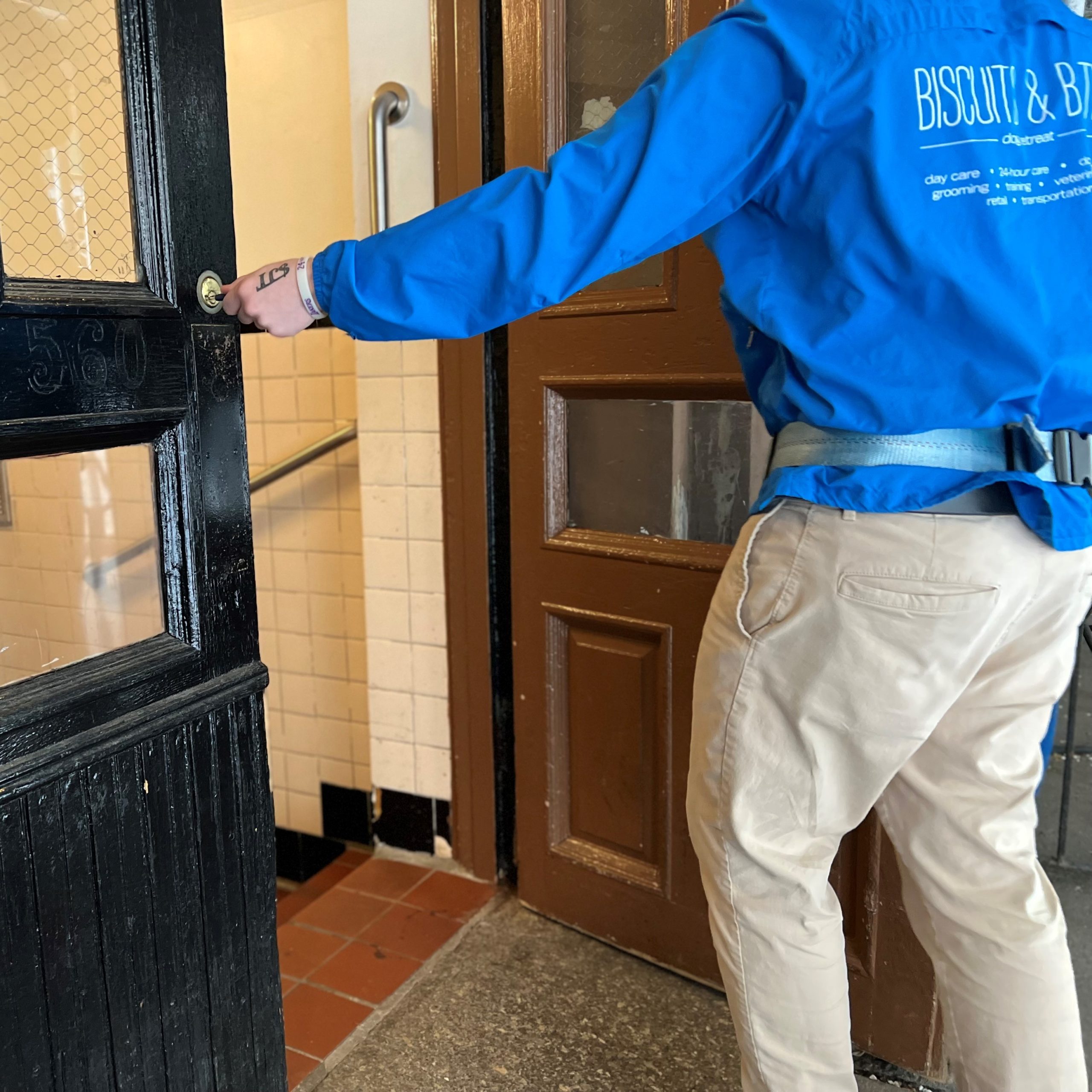 A person in a Biscuits & Bath jacket entering a building